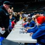 A row of tables with riders giving signatures during a track party.